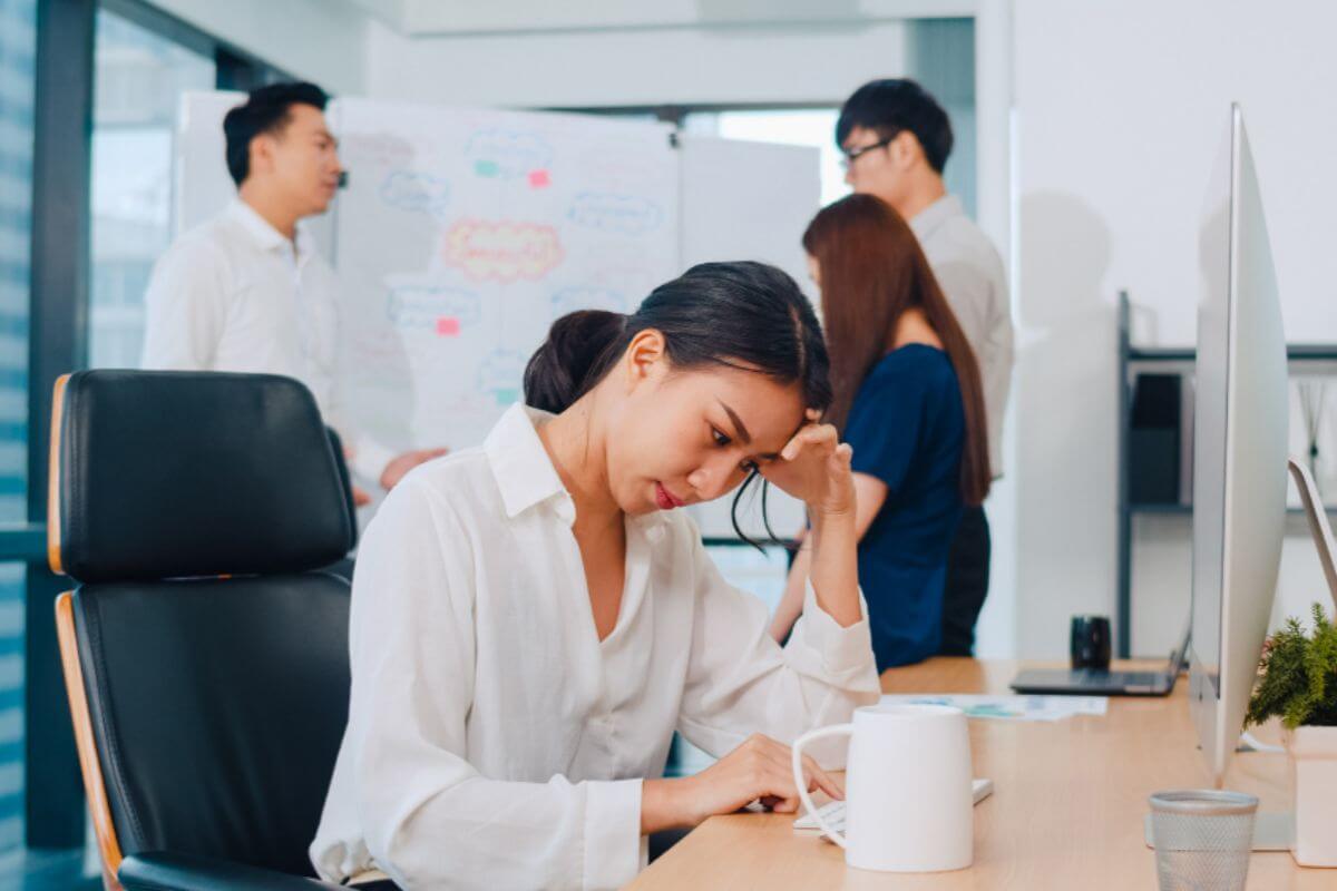 Woman in a workplace appearing hesitant to share her opinions with colleagues during a team discussion.