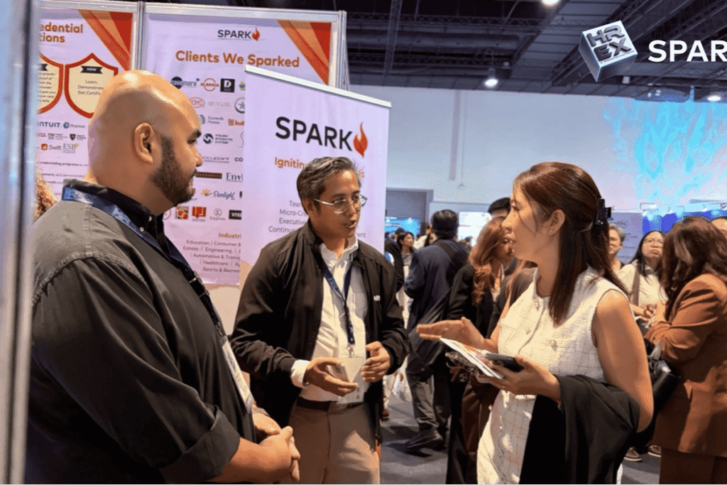 Team members discussing core services and client engagement strategies with a visitor at the SPARK booth