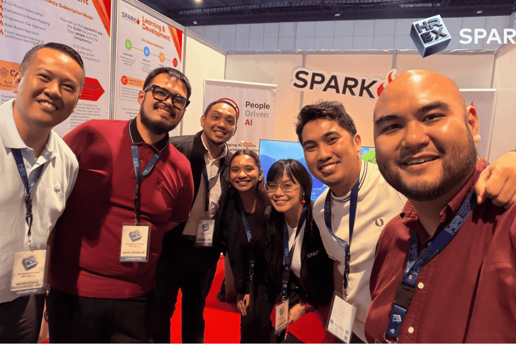 Team members smiling together for a group photo inside the SPARK Learning and Development exhibition area.