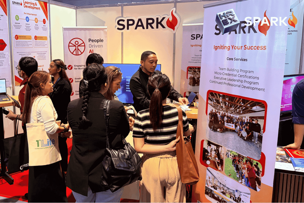 Visitors browsing training materials and team-building program information at the SPARK exhibit counter.